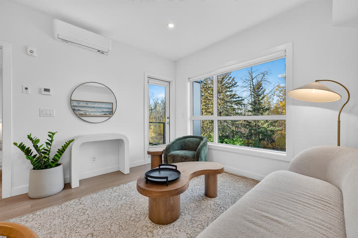Living room with curved sofa, white oak floors and ravine views