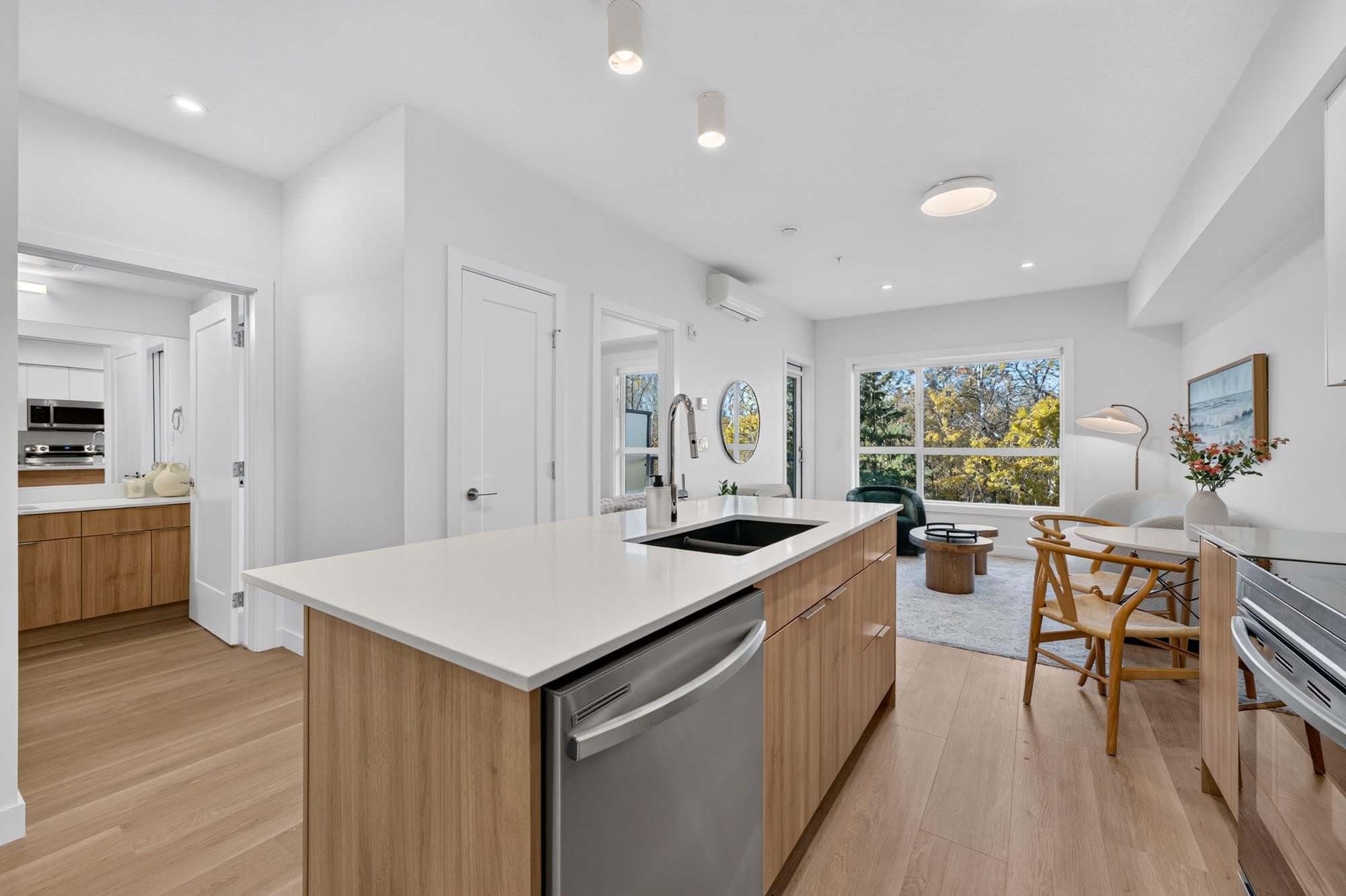 Kitchen with white oak and matte white cabinetry, quartz island and stainless appliances, open to the dining area